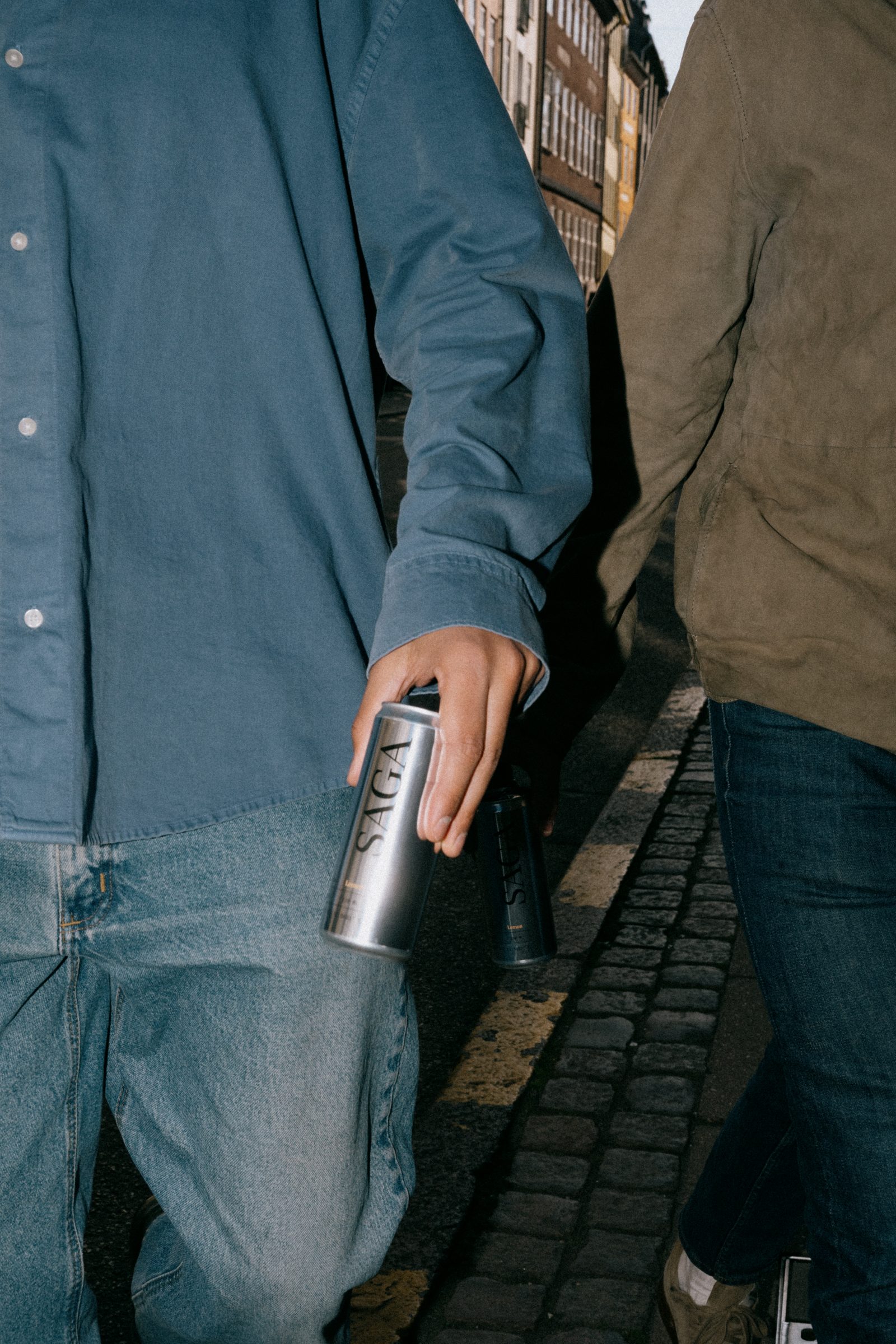 Two people walking with SAGA cans